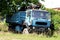 Light blue partially rusted old vintage retro truck with strong lifting crane in back left in nature abandoned by owners