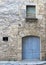 Light blue wooden door in a stone facade. Small window Elegant entrance Rustic