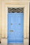 Light blue wooden entrance door with ornated sign and knocker