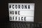 Light box with the inscription: #CORONA HOME OFFICE is behind a black computer keyboard against a black background
