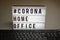 Light box with the inscription: #CORONA HOME OFFICE is behind a black computer keyboard against a gray background