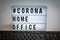 Light box with the inscription: #CORONA HOME OFFICE is behind a black computer keyboard against a gray background