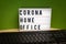 Light box with the inscription Corona Home Office stands on a desk and in front of it is a keyboard