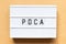 Light box with word PDCA business abbreviation of plan do check act on wood background