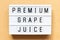 Light box with word premium grape juice on wood background