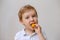 A light boy todler eats an orange fruit.