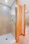 Light brown bathroom interior with wooden storage combination and shower.