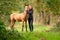 A light brown buckskin foal, the female owner stands next to the stallion Autumn Sun