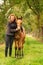 A light brown buckskin foal, the female owner stands next to the stallion Autumn Sun