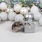 Light brown Dzungarian hamster near a silver gift box. Christmas card with white and silver balls, garland, tinsel