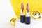 Light brown lipsticks on a shiny yellow background with Christmas golden balls . Christmas gift for women. Festive decoration of c