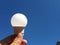 light bulb on blue sky background in human hand. Electricity concept. Saving electricity