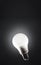 Light bulb floating in dark empty black space and shining. Power saving led light.
