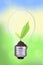 light bulb with fresh green leaves inside on green bokeh background