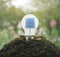 Light Bulb with solar cell inside on pile of soil over blur pink
