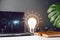 Light bulb with technology theme hologram, laptop, monstera leaves, eyeglasses and notebook with copy space on grey background