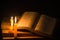 Light candle with holy bible and cross or crucifix on old wooden background in church.Candlelight and open book on vintage wood