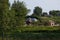 Light clouds in the warm summer sky over village with small light houses from brick far away in the forest. Small lake is near. Su