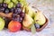 Light and dark grapes in a wooden bowl with an apple pear plum a