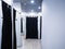 Light fitting room with white walls and black curtains on the booths. Clothing store. Focus on dark curtain