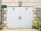 Light garage door with a padlock in the wall of a house with rough decorative masonry