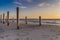 The light of golden hour at the beach with wooden piles and hearts drawings in the sand