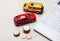 On a light gray background, red and yellow cars, a white calculator and cash