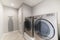 Light gray laundry room with tiles, washer, dryer and storage room