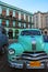 Light green vintage classic yank tank Cuban taxi car of Cuba in front of old building in Havana