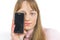 light-haired young woman holding her phone in front of her face, closeup shot white background