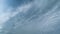 Light high clouds slide on sky. Layer of clouds in blue sky moving horizontal in opposite direction. Timelapse.