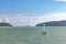 A light house in the sea and a cargo ship sailing in the background off the coast of Thailand