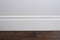 Light matte wall, white baseboard and tiles immitating hardwood flooring