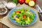 Light meal of green leaves of lettuce, yellow and red tomatoes, olive oil on wooden table