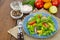 Light meal of green leaves of lettuce, yellow and red tomatoes, olive oil on wooden table