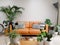 Light modern living room with brown leather couch, cowhide rug and numerous green houseplants creating an urban jungle