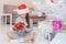 Light photo of cute kid sitting with gift in hands, like a little gnome in christmas decorated room.