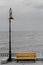 Light pole with colored bench on seafront, seaside, cloudy day, dawn