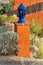 Light post in front yard with orange stucco exterior and slick blue lamp on top with light inside in desert environment