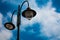 Light post with two bulbs and blue cloudy sky background. Outdoor street lights. Cast iron lamp. Large lantern. Lighting pole. Ill