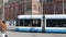 Light rail tram traveling on rails through pedestrian square in front of historic