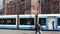 Light rail tram traveling on rails through pedestrian square in front of historic