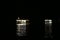 The light reflections of two floating fuel stations on the Amazon river during night time, at the busy port of Manaus, Brazil