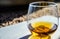 light refracting through a glass of amber colored liquid with a wedding ring at the bottom