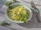 Light salad with fresh katusta and cucumbers with spicy herbs on a round lettuce plate on a plank table a few sprigs of spicy