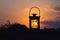 Light of setting sun in silhouette of lantern outside the city.