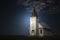 light shining on old country church at night time.