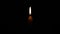 The light of a single candle flame swayed in the soft breeze and was beautifully lit in the darkness.