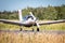 Light single engine aircraft in white accelerates for takeoff