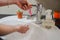 Light-skinned Asian woman washing foamy hands in the bathroom sink with soap.